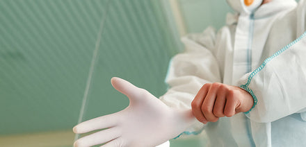 medical personnel putting on white gloves preparing to work 