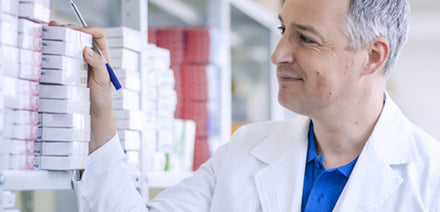 A pharmacist managing pharmaceutical inventory and medicine stock on warehouse shelves
